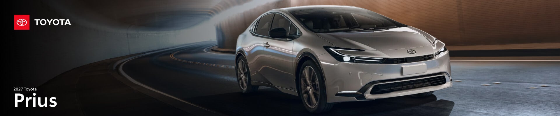 A front three-quarter action shot of a silver 2027 Toyota Prius driving through a city tunnel.
