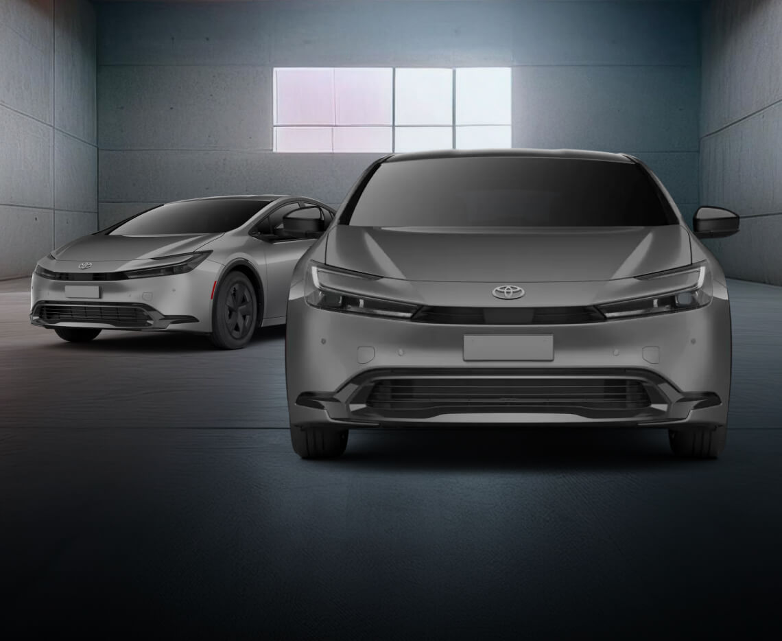 Front and three-quarter views of a silver Toyota Prius LE in a dark warehouse.